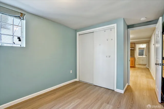 an empty room with wooden floor and a bathroom
