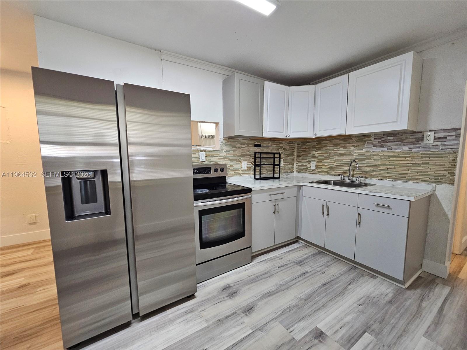 1727 Fletcher Street, Unit 1 Hollywood, FL 33020 - Photo 12 of 31 a kitchen with a refrigerator stove and white cabinets