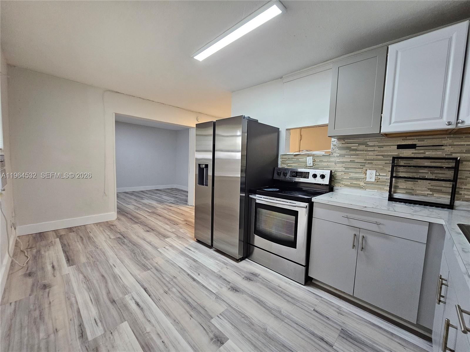 1727 Fletcher Street, Unit 1 Hollywood, FL 33020 - Photo 13 of 31 a kitchen with granite countertop wooden floors stainless steel appliances and cabinets