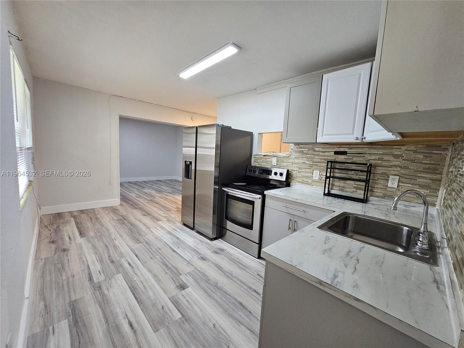 1727 Fletcher Street, Unit 1 Hollywood, FL 33020 - Photo 16 of 31 a kitchen with granite countertop wooden floors appliances and cabinets