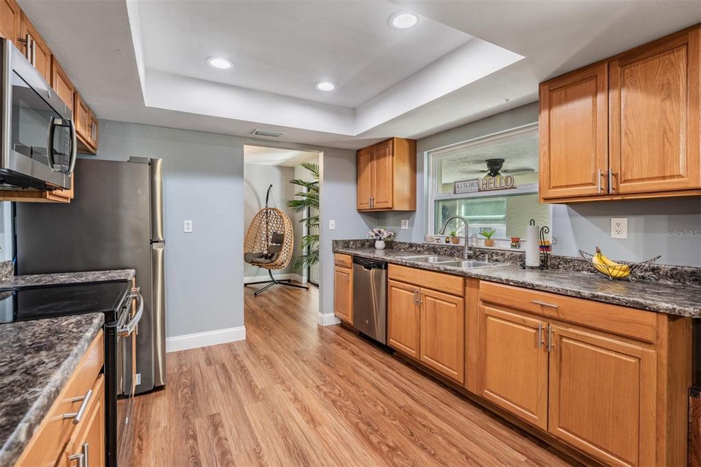 18631 San Rio Circle Lutz, FL 33549 - Photo 11 of 39 a kitchen with granite countertop wooden floors a stove and white stainless steel appliances