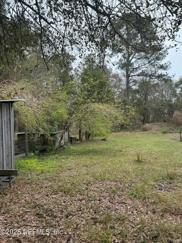 a view of a yard with plants and wooden fence