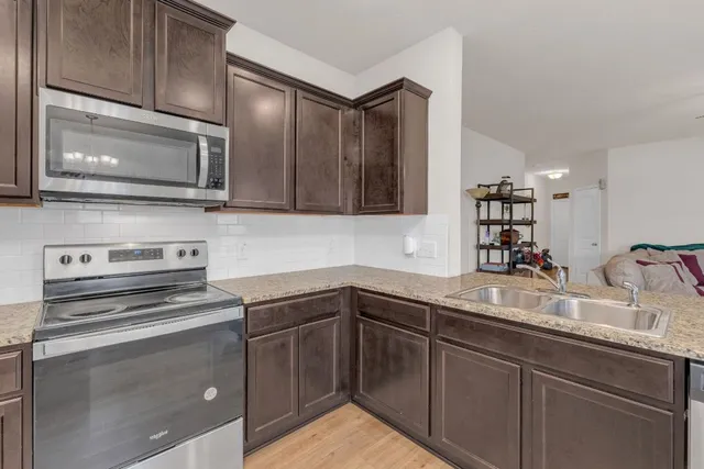 a kitchen with stainless steel appliances granite countertop a sink stove and microwave