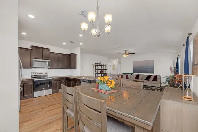 a kitchen with stainless steel appliances a stove a refrigerator a sink a stove and chairs with wooden floor