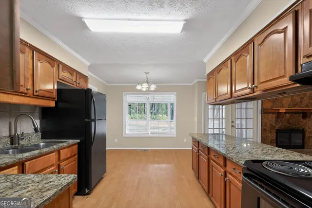 a kitchen with stainless steel appliances granite countertop a stove top oven a sink dishwasher a refrigerator and cabinets with wooden floor