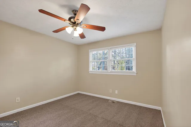 an empty room with a window and a ceiling fan