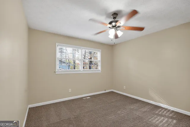 an empty room with windows and fan