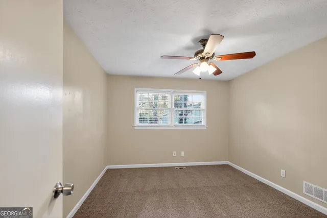 an empty room with windows and fan