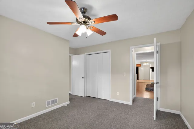 a view of an empty room and bathroom with a fan