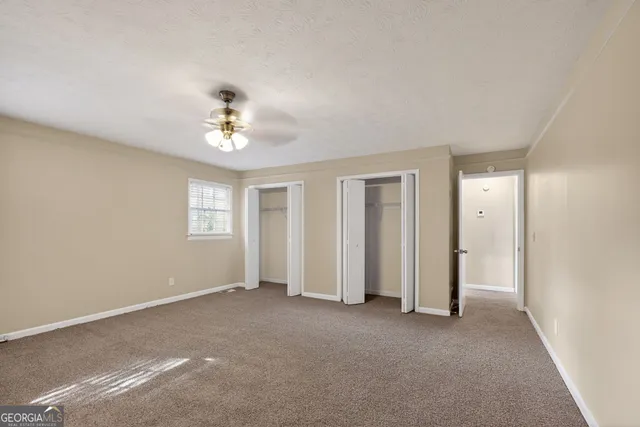 a view of a big room with windows and chandelier fan