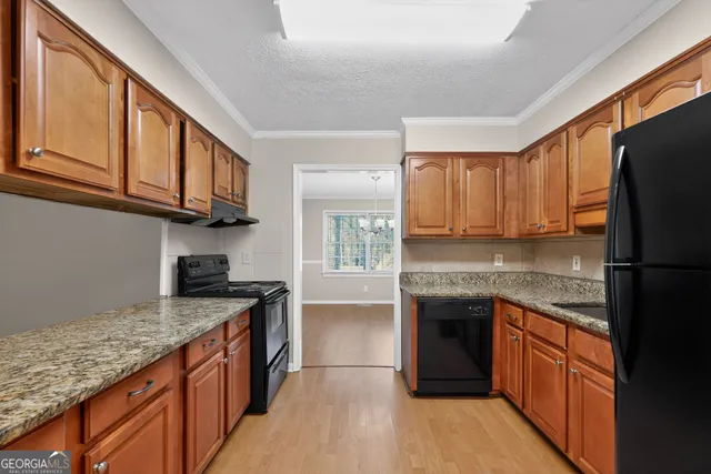 a kitchen with stainless steel appliances granite countertop a stove top oven a sink dishwasher and a refrigerator with wooden cabinets