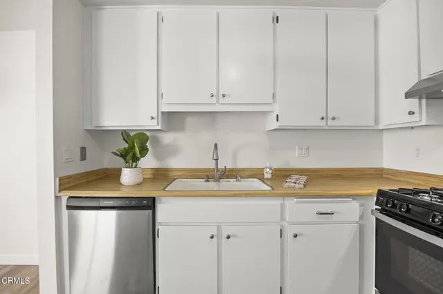 a kitchen with stainless steel appliances granite countertop a sink a stove white cabinets and a granite counter tops