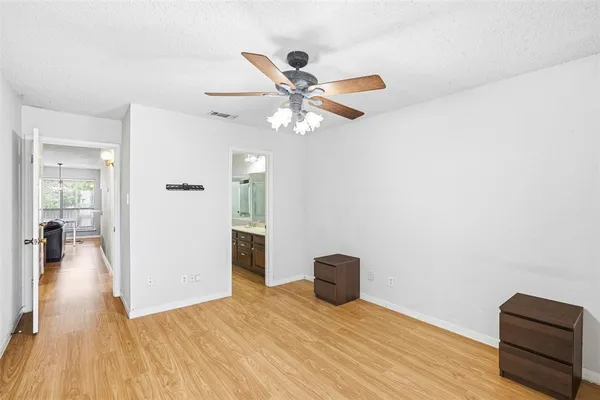 a view of an empty room with wooden floor and a ceiling fan