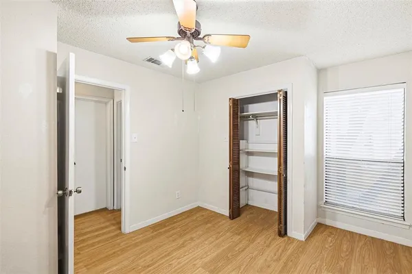 an empty room with wooden floor closet and windows