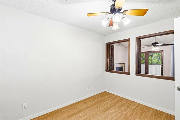 a view of an empty room with window and chandelier fan