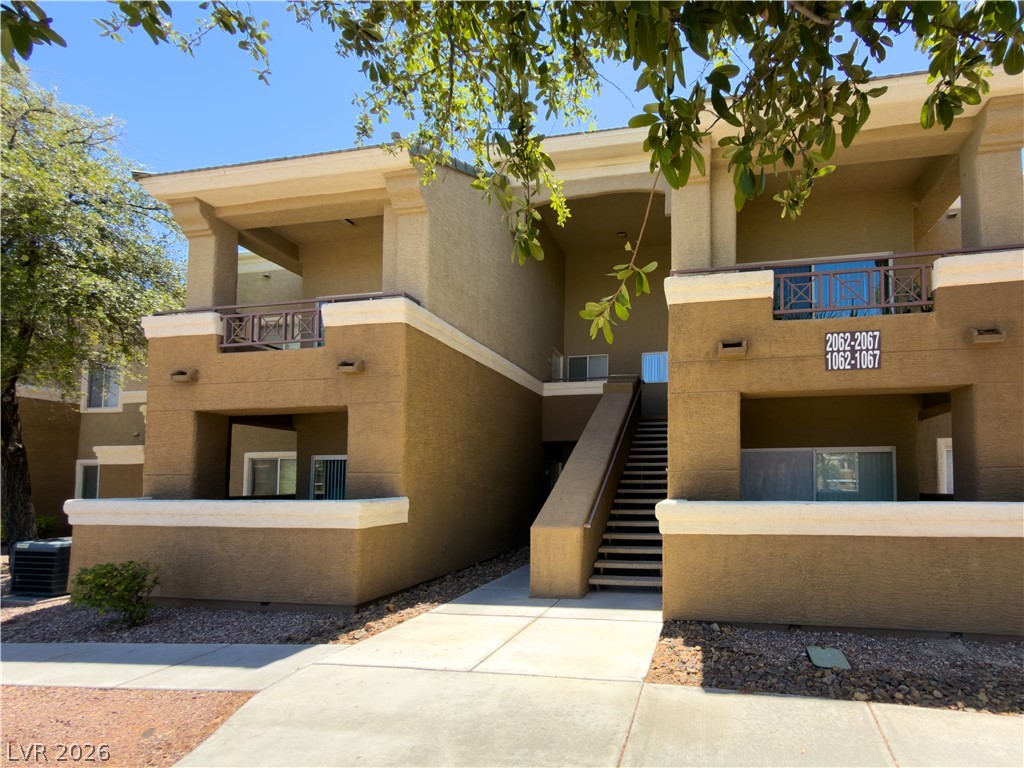 8070 West Russell Road, Unit 2063 Las Vegas, NV 89113 - Photo 1 of 9 A multi-level apartment building features balconies and a central outdoor staircase.
