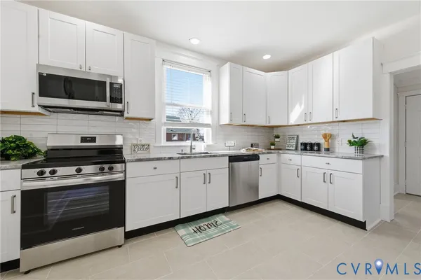 a kitchen with granite countertop a stove top oven microwave and cabinets