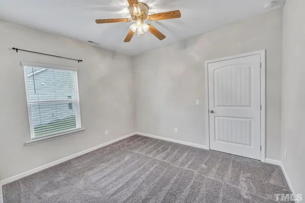 an empty room with windows and fan