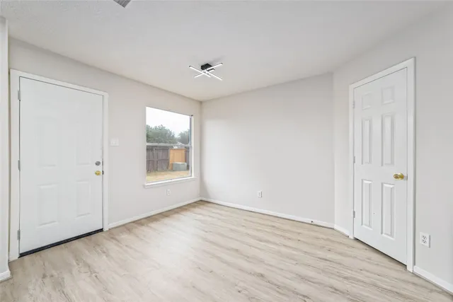 a view of an empty room with wooden floor and a window