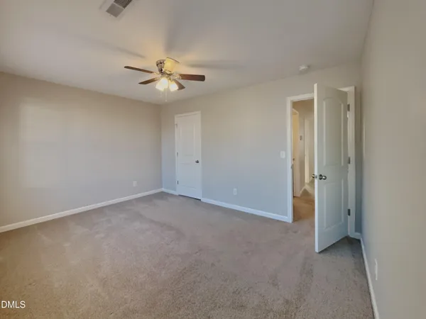 an empty room with closet and a ceiling fan