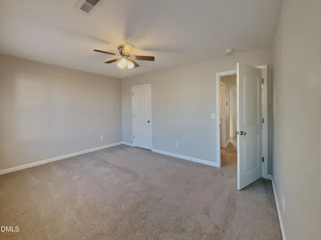 an empty room with closet and a ceiling fan