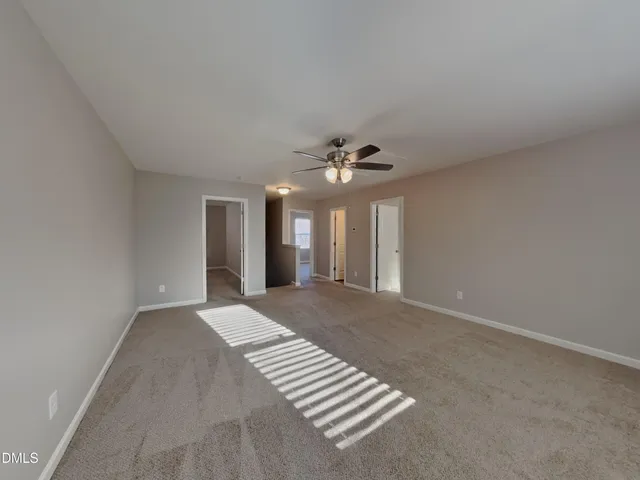 a view of an empty room with a chandelier fan