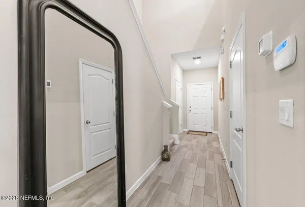 a view of a hallway with wooden floor and a bathroom