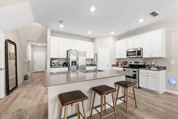 a kitchen with stainless steel appliances granite countertop a stove top oven a sink dishwasher a dining table and chairs with wooden floor