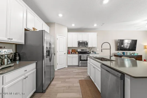 a kitchen with stainless steel appliances granite countertop a sink refrigerator and cabinets