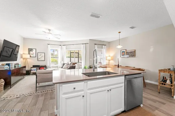 a kitchen with sink stove and white cabinets with wooden floor