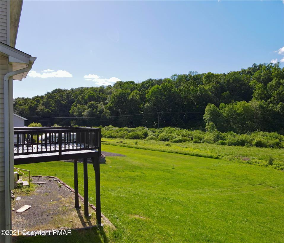 1110 Misty Ridge East Stroudsburg, PA 18302 - Photo 11 of 43 A spacious wooden deck extends over a verdant backyard, opening to a tranquil, tree-lined landscape.