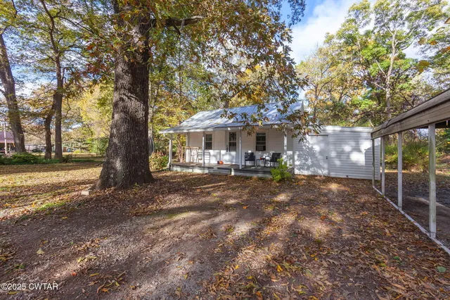a view of a house with large tree and a yard