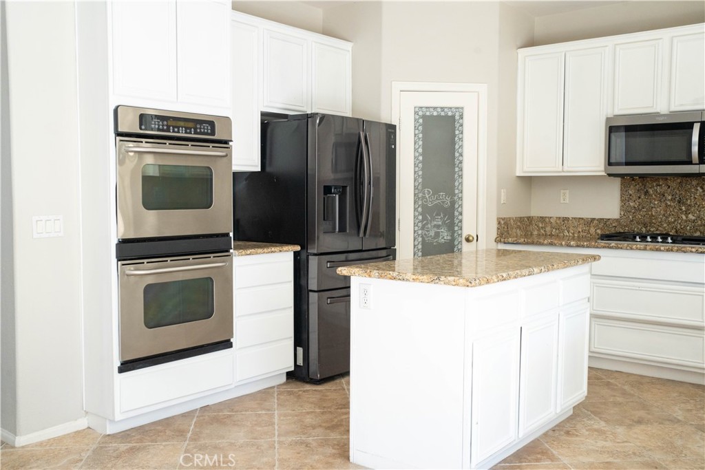 36719 Torrey Pines Drive Beaumont, CA 92223 - Photo 29 of 56 a kitchen with granite countertop a refrigerator and a stove