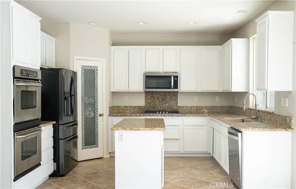 36719 Torrey Pines Drive Beaumont, CA 92223 - Photo 31 of 56 a kitchen with a sink a microwave a refrigerator and cabinets