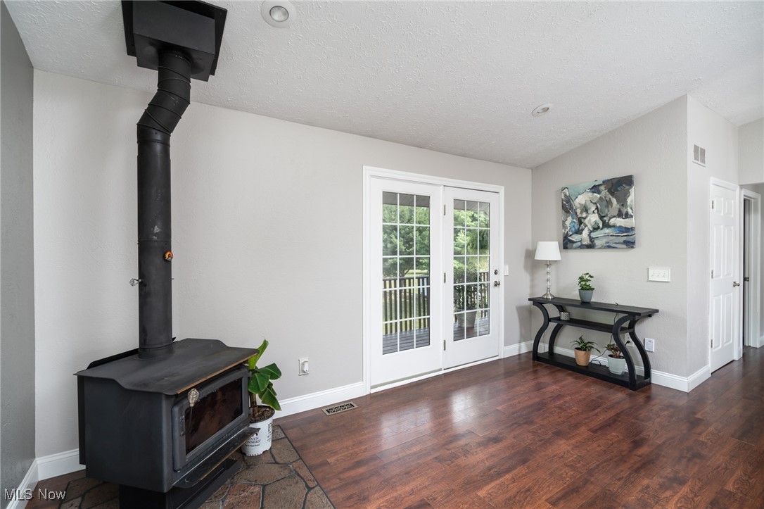 12345 Darrow Road Vermilion, OH 44089 - Photo 30 of 50 Living room featuring a textured ceiling, a wood stove, dark hardwood / wood-style floors, french doors, and lofted ceiling