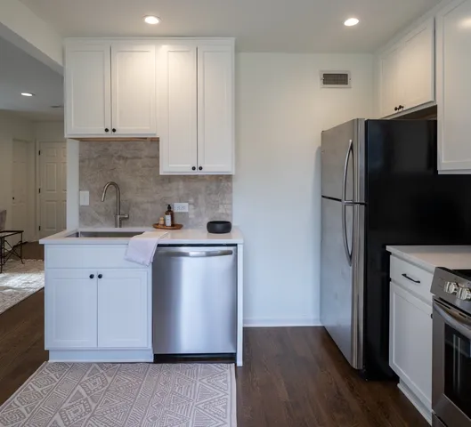 a kitchen with stainless steel appliances granite countertop a refrigerator a stove a sink and white cabinets