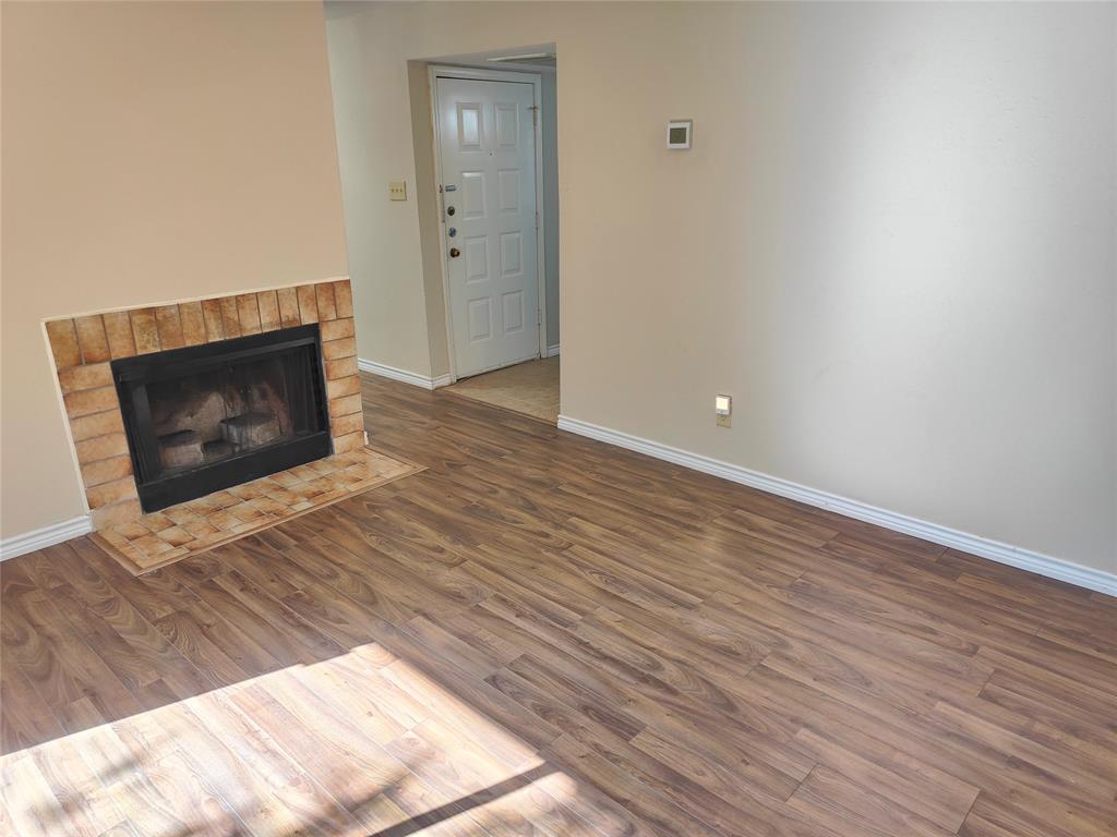4748 Old Bent Tree Lane, Unit 207 Dallas, TX 75287 - Photo 4 of 20 a view of an empty room with wooden floor and a fireplace