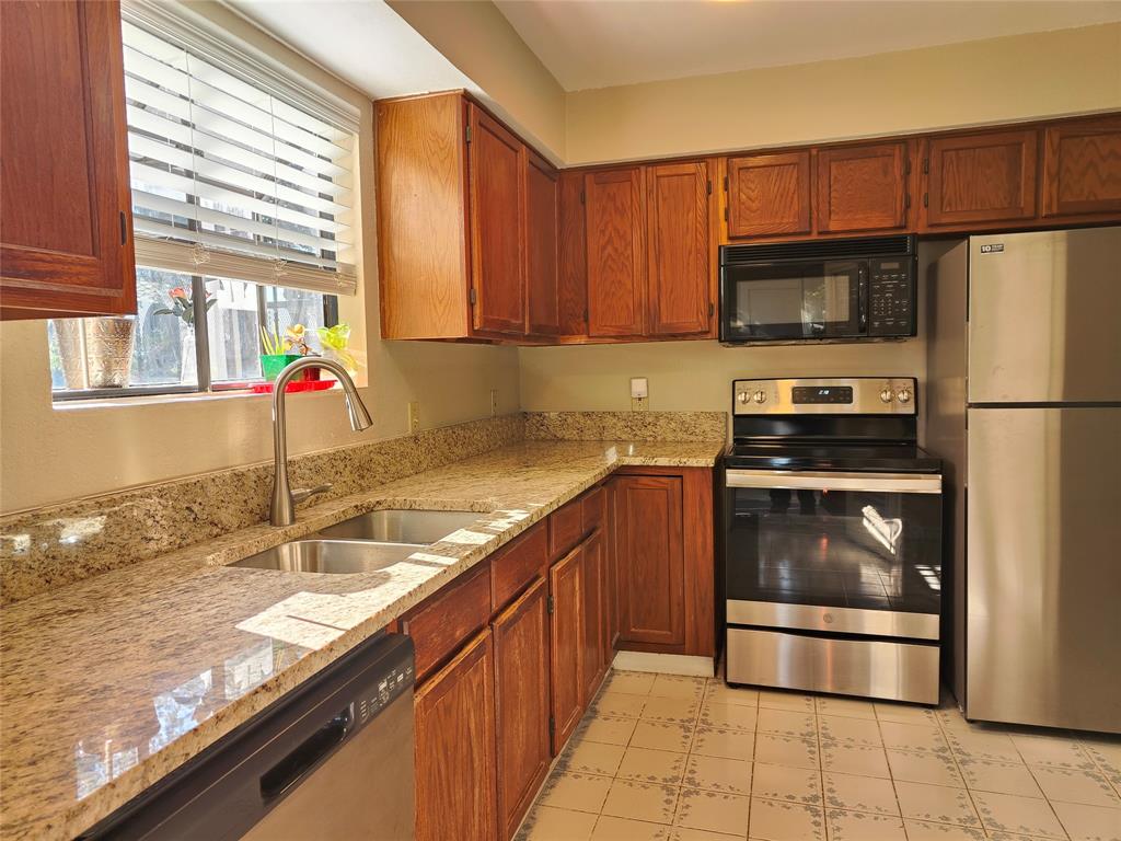 4748 Old Bent Tree Lane, Unit 207 Dallas, TX 75287 - Photo 6 of 20 a kitchen with granite countertop a sink a counter top space cabinets and stainless steel appliances