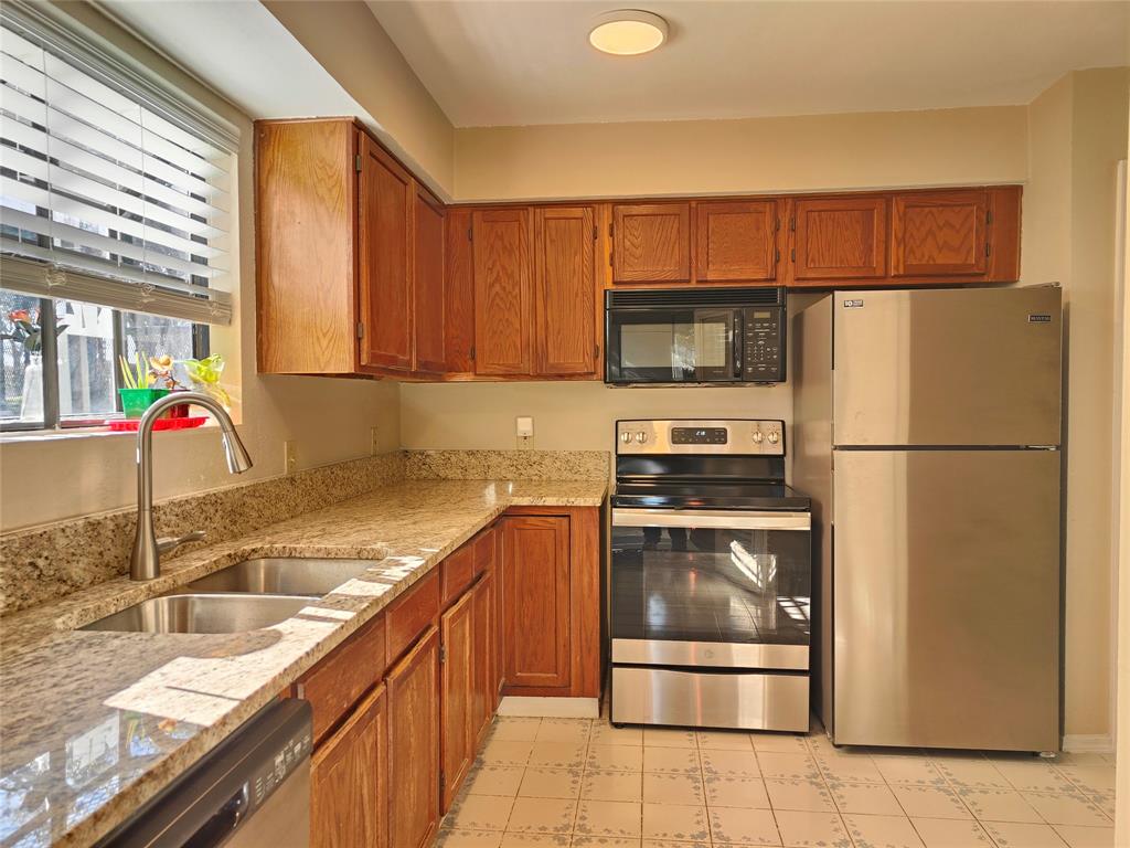 4748 Old Bent Tree Lane, Unit 207 Dallas, TX 75287 - Photo 8 of 20 a kitchen with stainless steel appliances granite countertop a refrigerator a stove and a sink