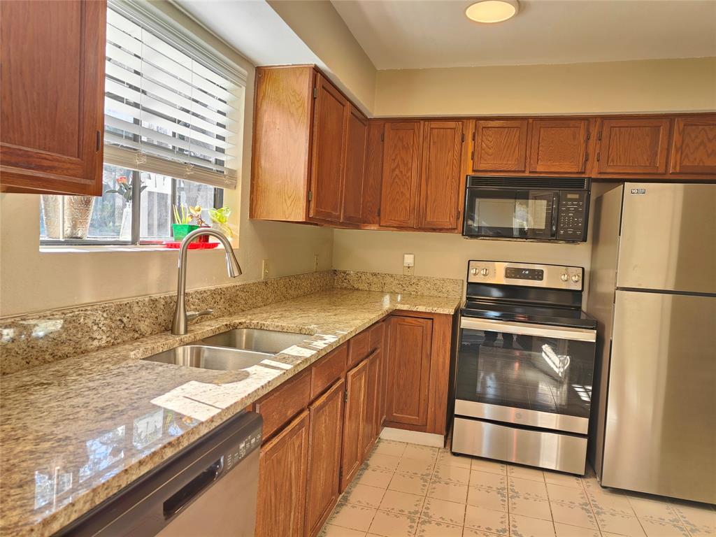 4748 Old Bent Tree Lane, Unit 207 Dallas, TX 75287 - Photo 9 of 20 a kitchen with granite countertop a sink stainless steel appliances and cabinets