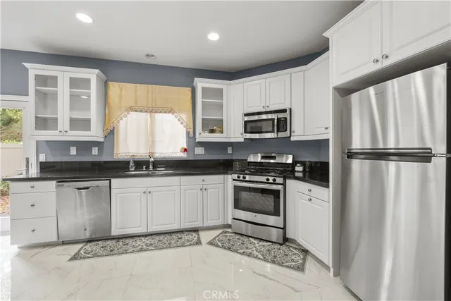 a kitchen with granite countertop a refrigerator stove top oven and sink
