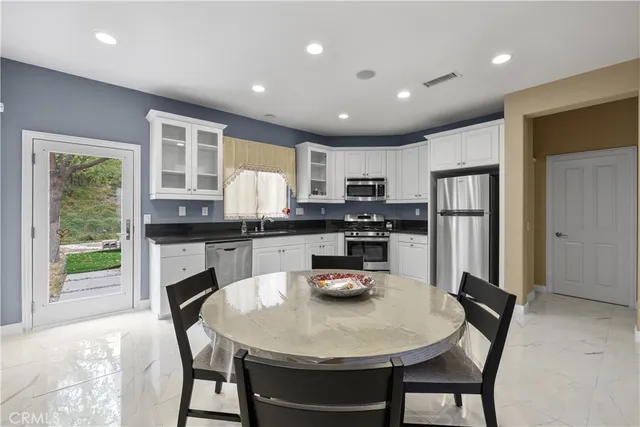 a kitchen with stainless steel appliances granite countertop a stove a refrigerator a sink a dining table and chairs