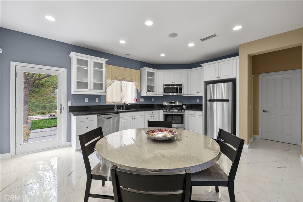 17408 Winter Pine Way Canyon Country, CA 91387 - Photo 7 of 29 a kitchen with stainless steel appliances granite countertop a stove a refrigerator a sink a dining table and chairs