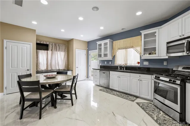 a kitchen with stainless steel appliances kitchen island granite countertop a stove a sink a microwave a dining table and chairs