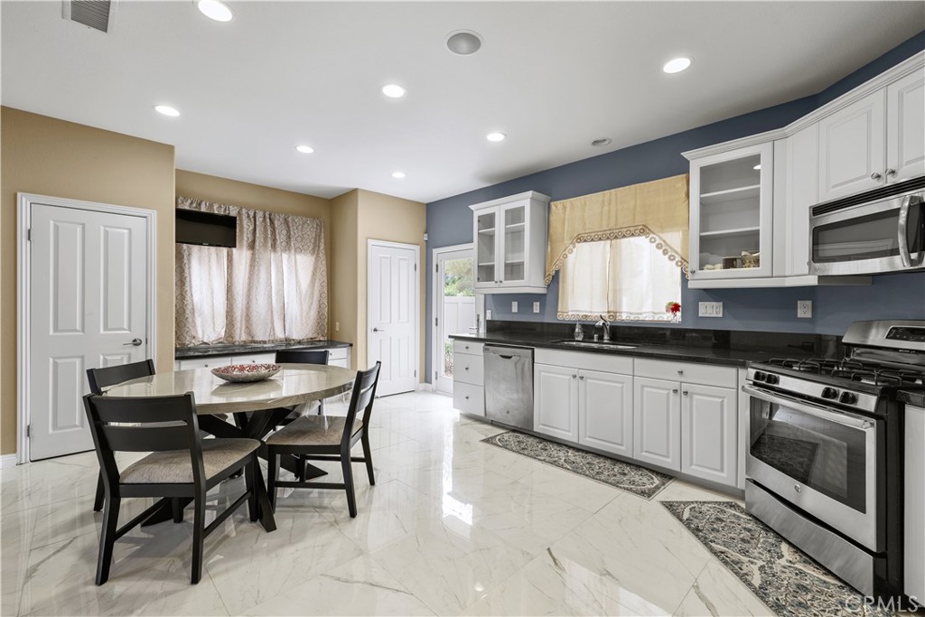 17408 Winter Pine Way Canyon Country, CA 91387 - Photo 10 of 29 a kitchen with stainless steel appliances kitchen island granite countertop a stove a sink a microwave a dining table and chairs