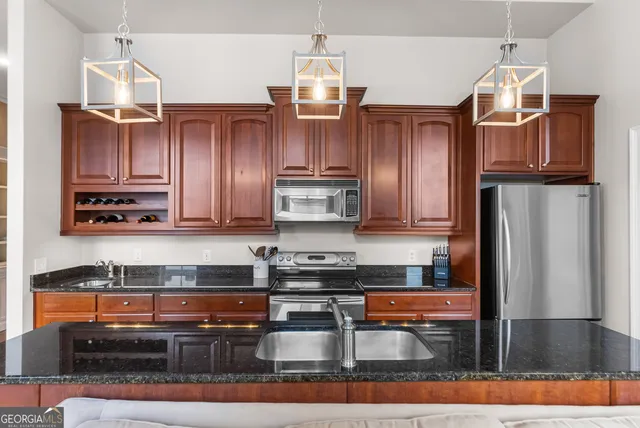 a kitchen with stainless steel appliances granite countertop a refrigerator a stove and a sink