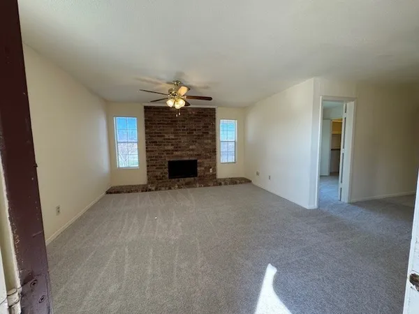 an empty room with a fireplace and chandelier fan