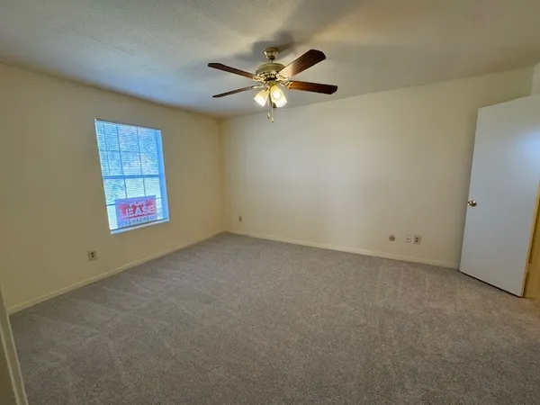 an empty room with windows and fan