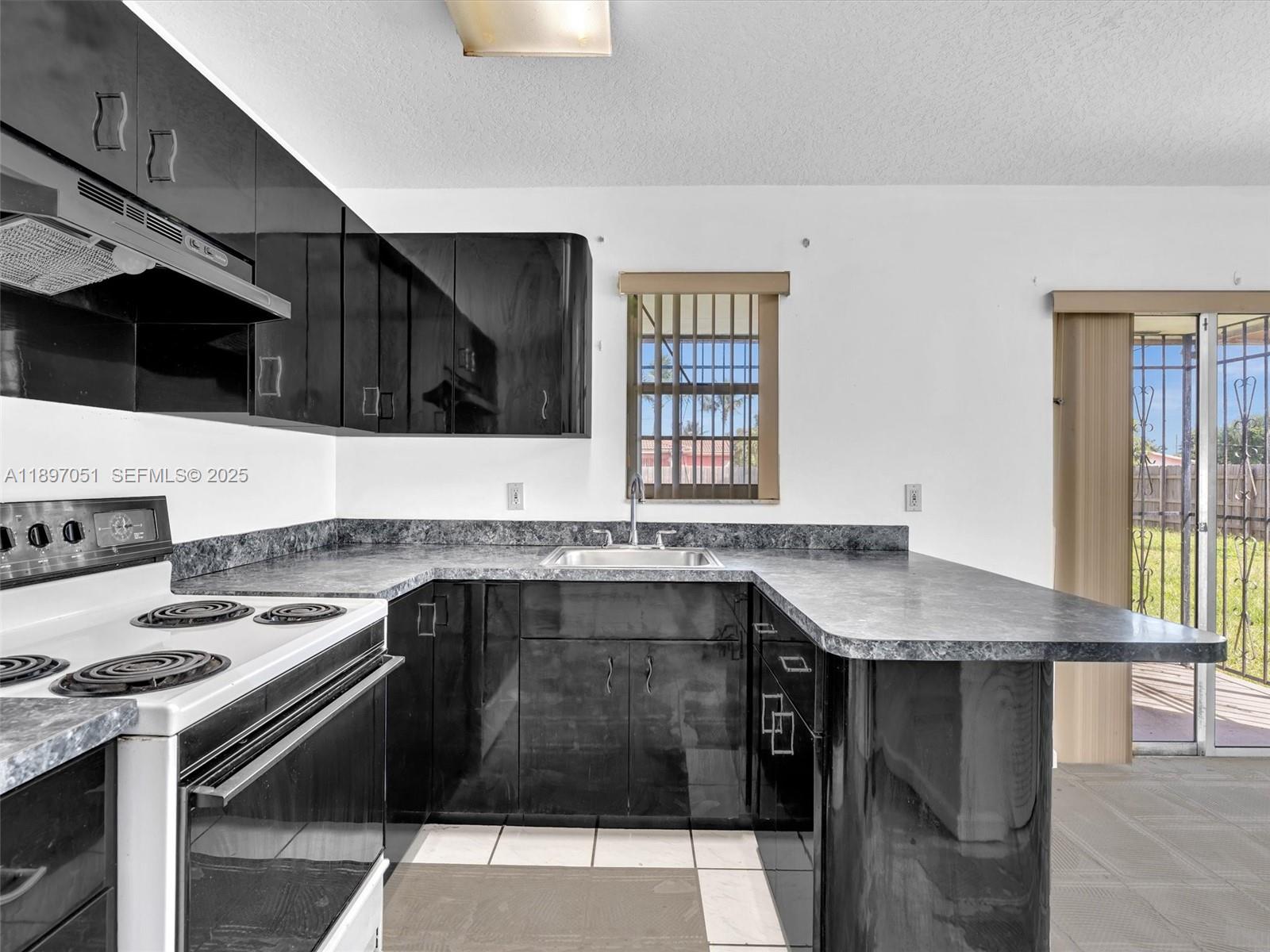 17995 Southwest 105th Avenue Miami, FL 33157 - Photo 28 of 45 a kitchen with granite countertop a stove a sink and a microwave