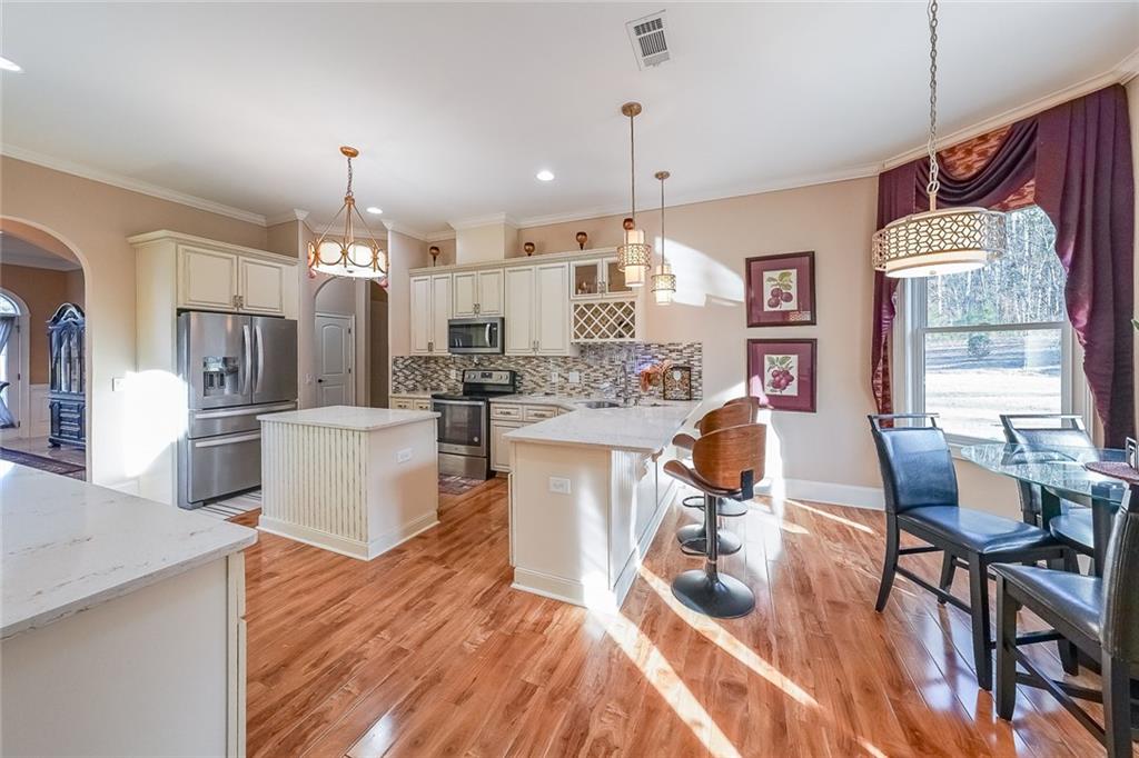 2425 Wild Oak Court Stockbridge, GA 30281 - Photo 17 of 39 a kitchen with stainless steel appliances kitchen island granite countertop a table chairs and a wooden floor
